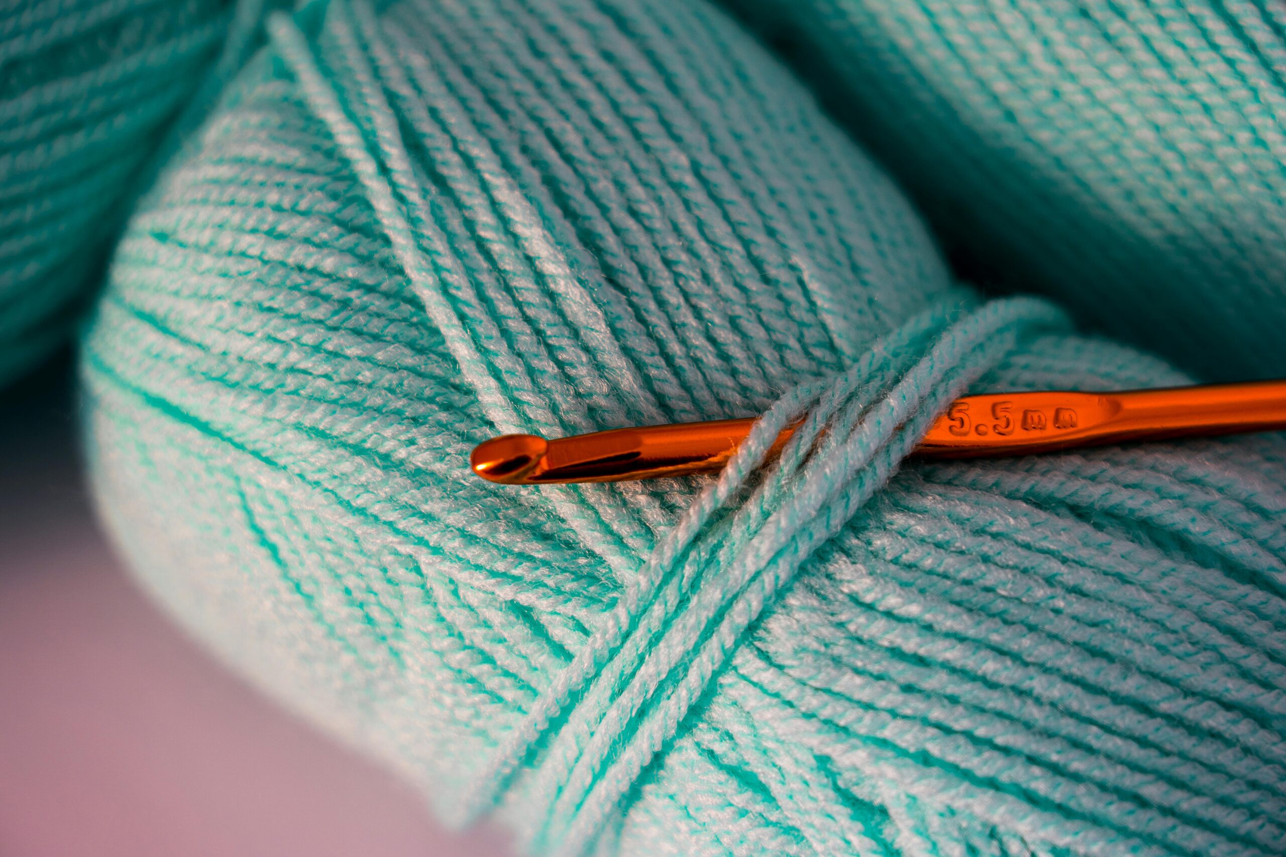 Welcome! Macro photograph of teal yarn with a crochet hook, highlighting texture and detail.